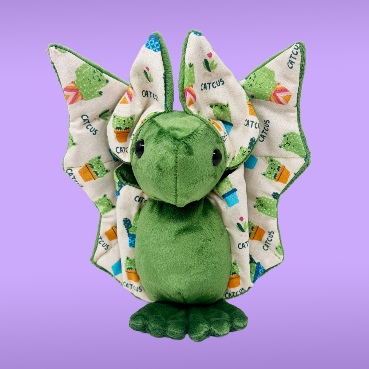 Green plush bat toy with patterned wings on a purple background