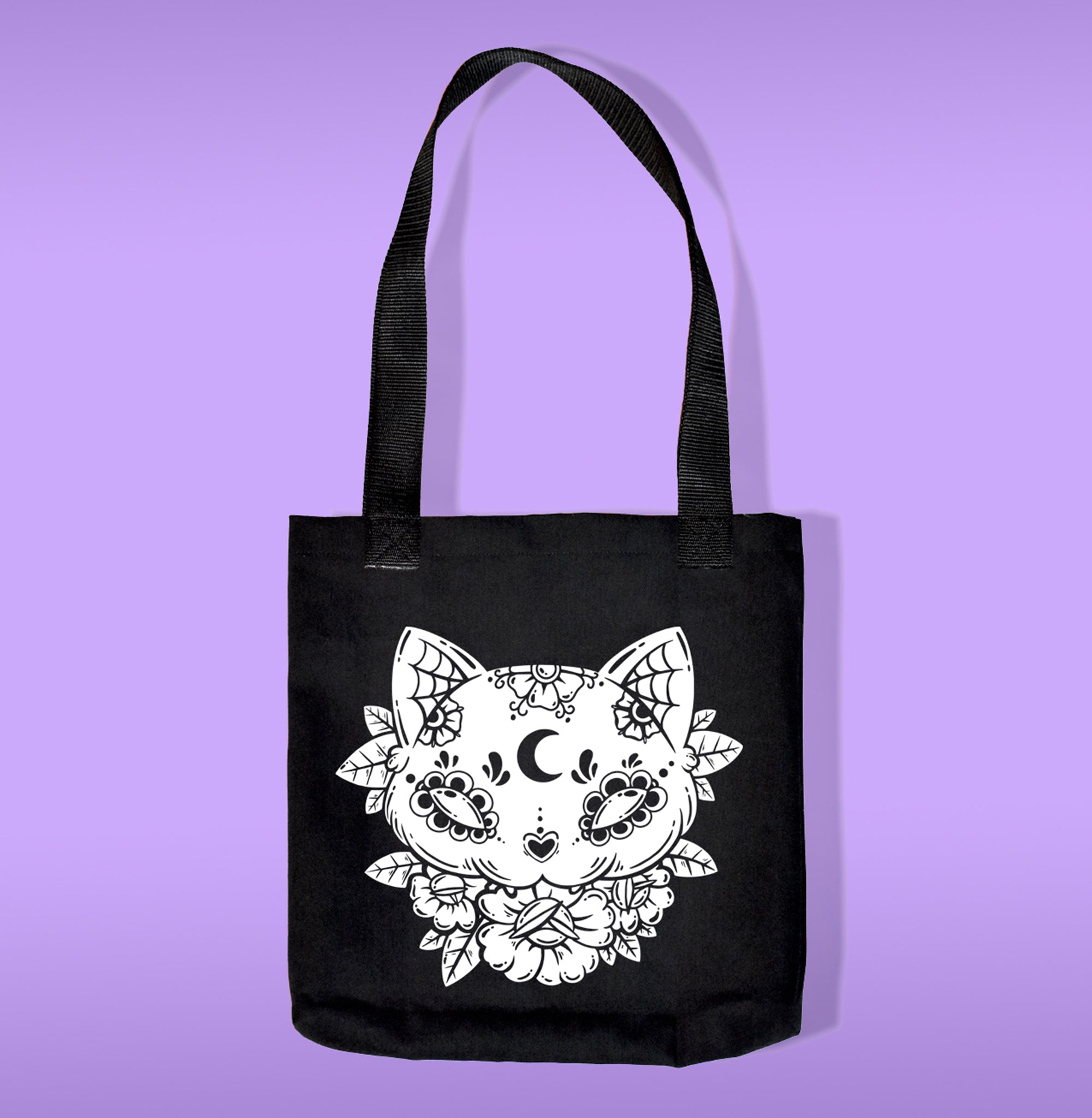 A black canvas bag with polypropelene straps. Features a cat sugar skull with flower heat transfer print