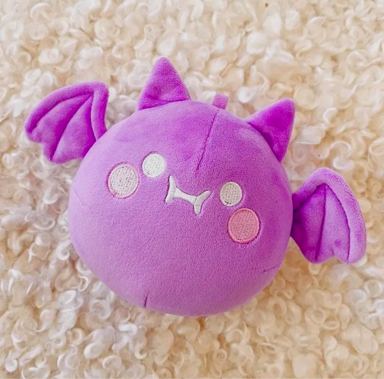 A 7.5” x 5” round purple plush bar keychain with a start lobster claw. Features a cute embroidered face.