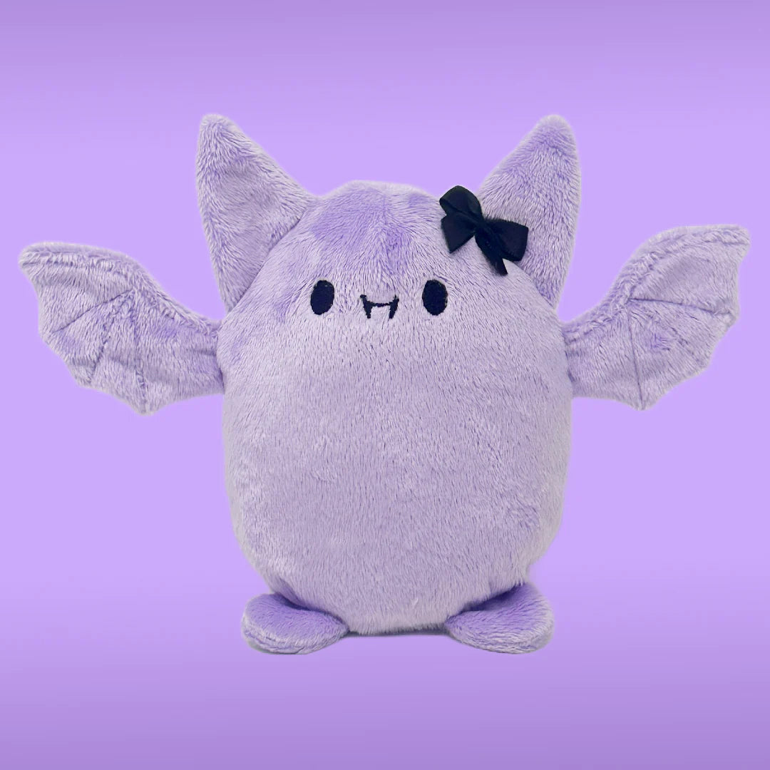 A pudgy Lavender Bat Plushy with a black bow. Has a cute smiley face with fangs.  