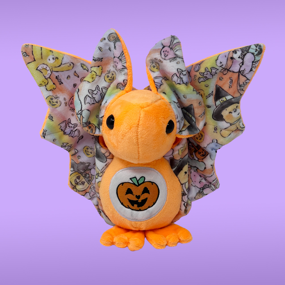 Plush toy with Halloween-themed wings on a purple background