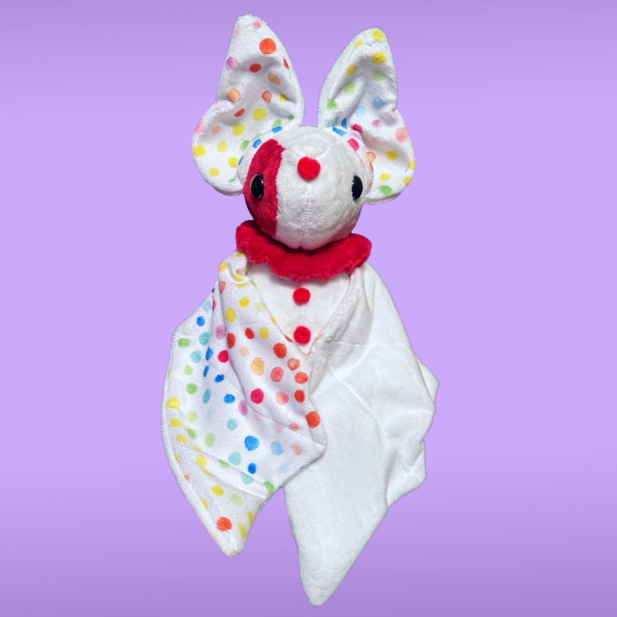 Plush toy with colorful polka dot ears and ruffle color on a purple background