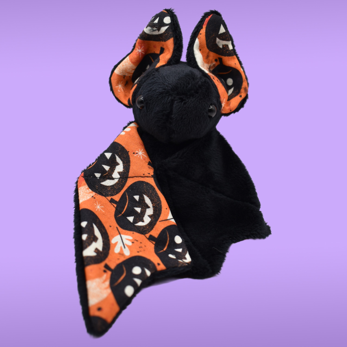 Handmade black Spookling bat plush with orange Halloween print wings featuring jack-o’-lanterns and spooky seasonal details
