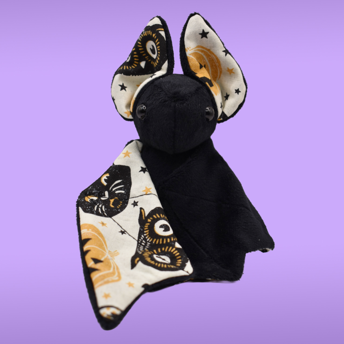 Handmade black Spookling bat plush with cream vintage Halloween fabric wings featuring pumpkins, owls, and stars.