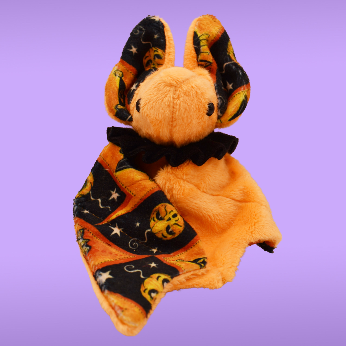 Handmade orange Spookling bat plush with vintage Halloween print wing details featuring pumpkins, stars, and spooky seasonal motifs.