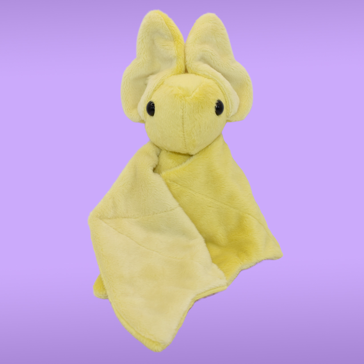 yellow Spookling bat plush with open
light yellow print wings displayed on a lavender background 