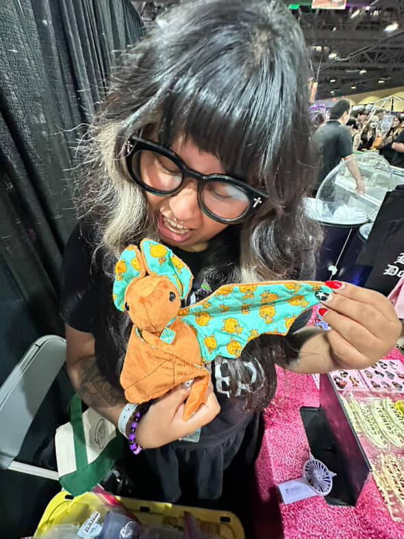 Person holding a plush toy with a colorful pattern at an event.