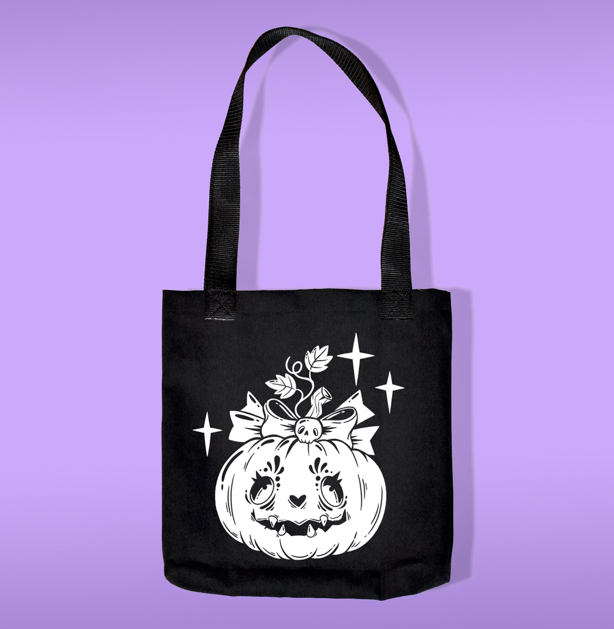 A black canvas bag with polypropelene straps. Features a pumkin with a bone bow heat transfer print