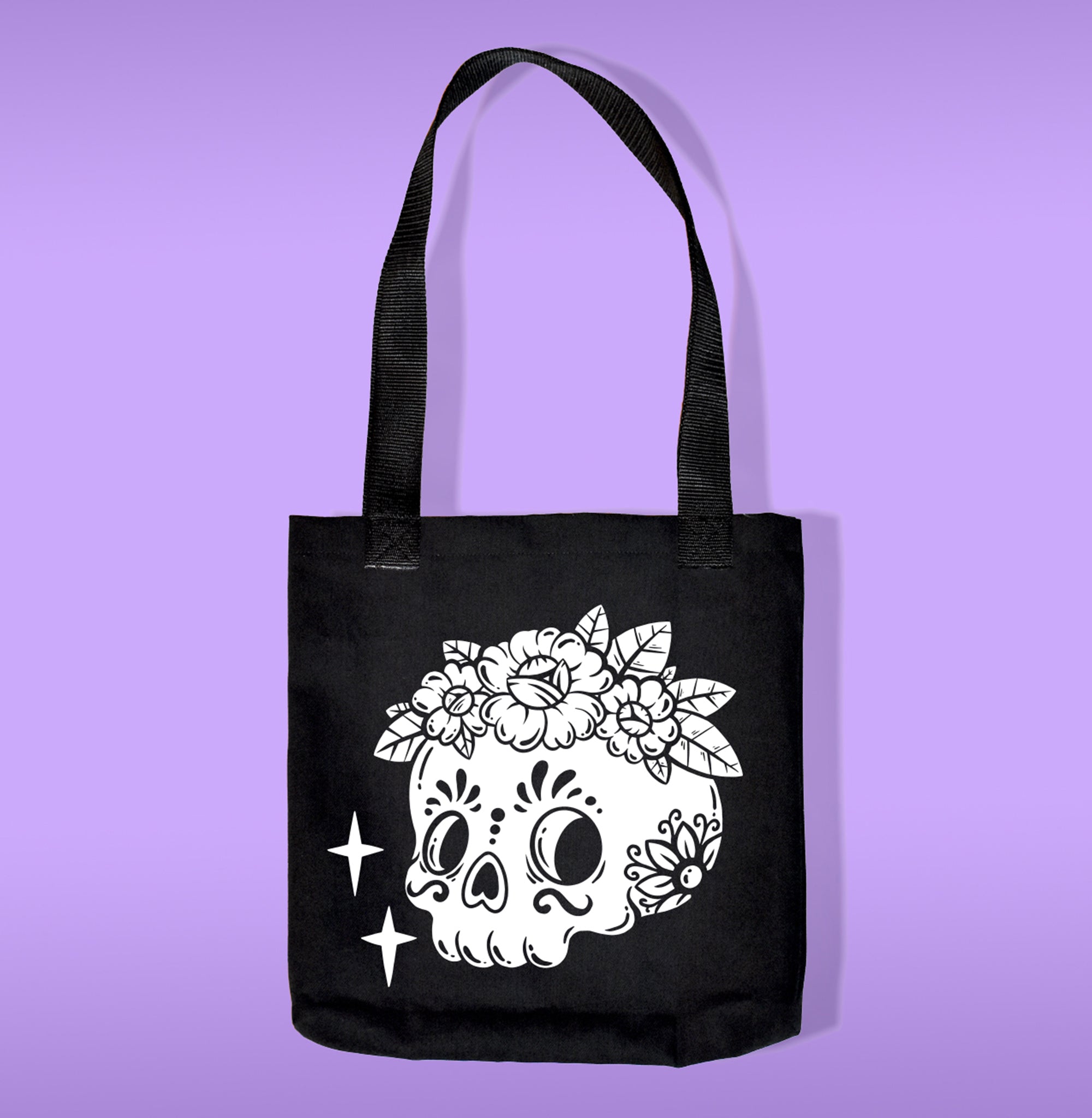 A black canvas bag with polypropelene straps. Features a sugar skull with flower heat transfer print