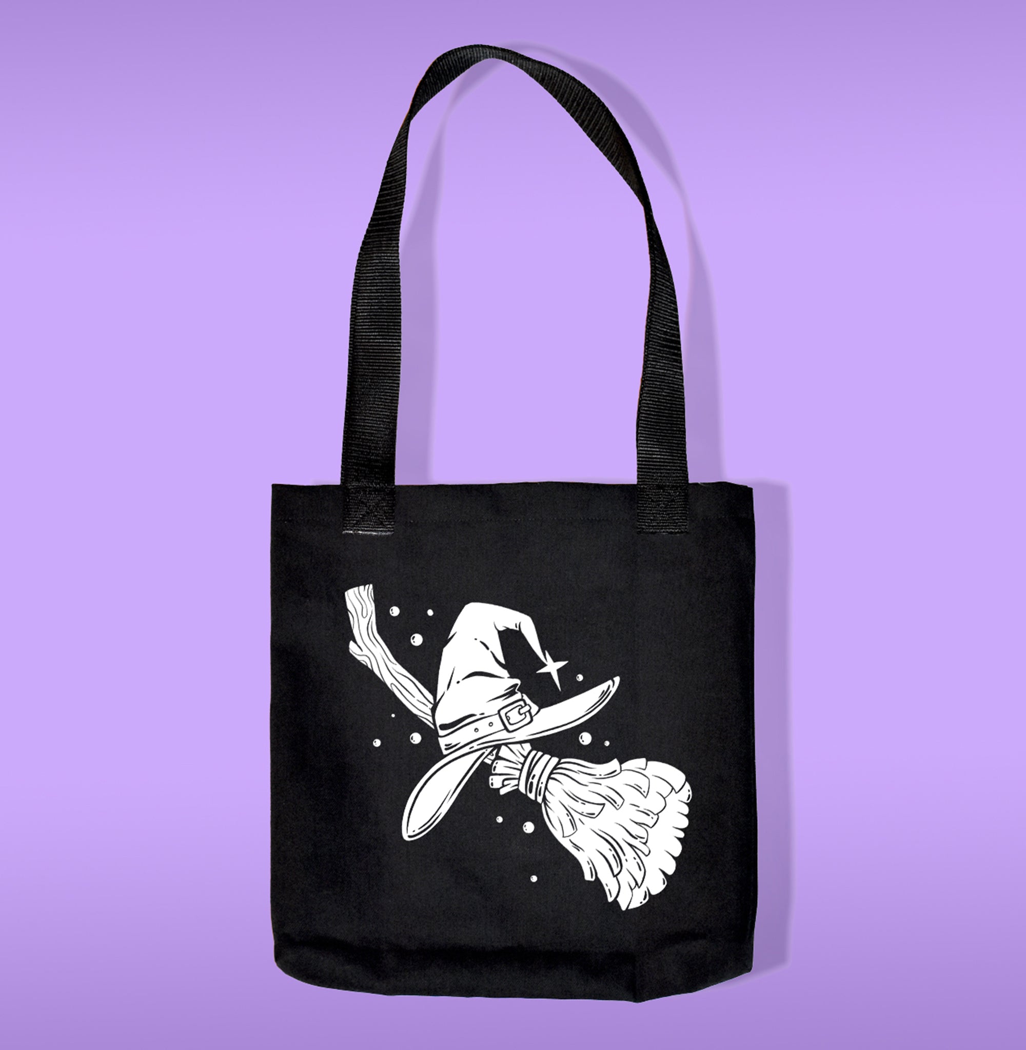 A black canvas bag with polypropelene straps. Features a broom and witch hat heat transfer print
